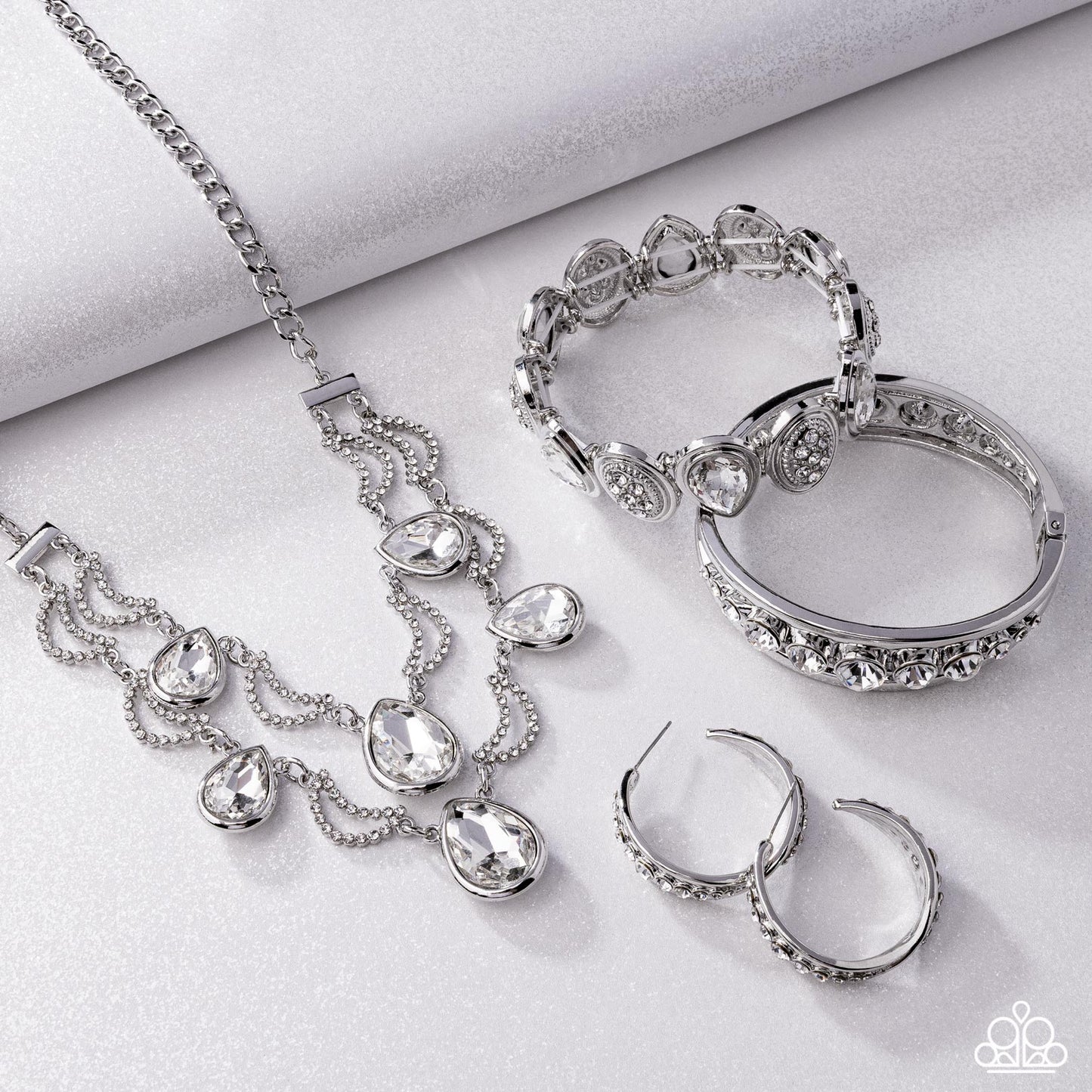 Silver ( Imitation)  jewelry set including necklace, bracelet, ring, and hoop earrings on a light gray background